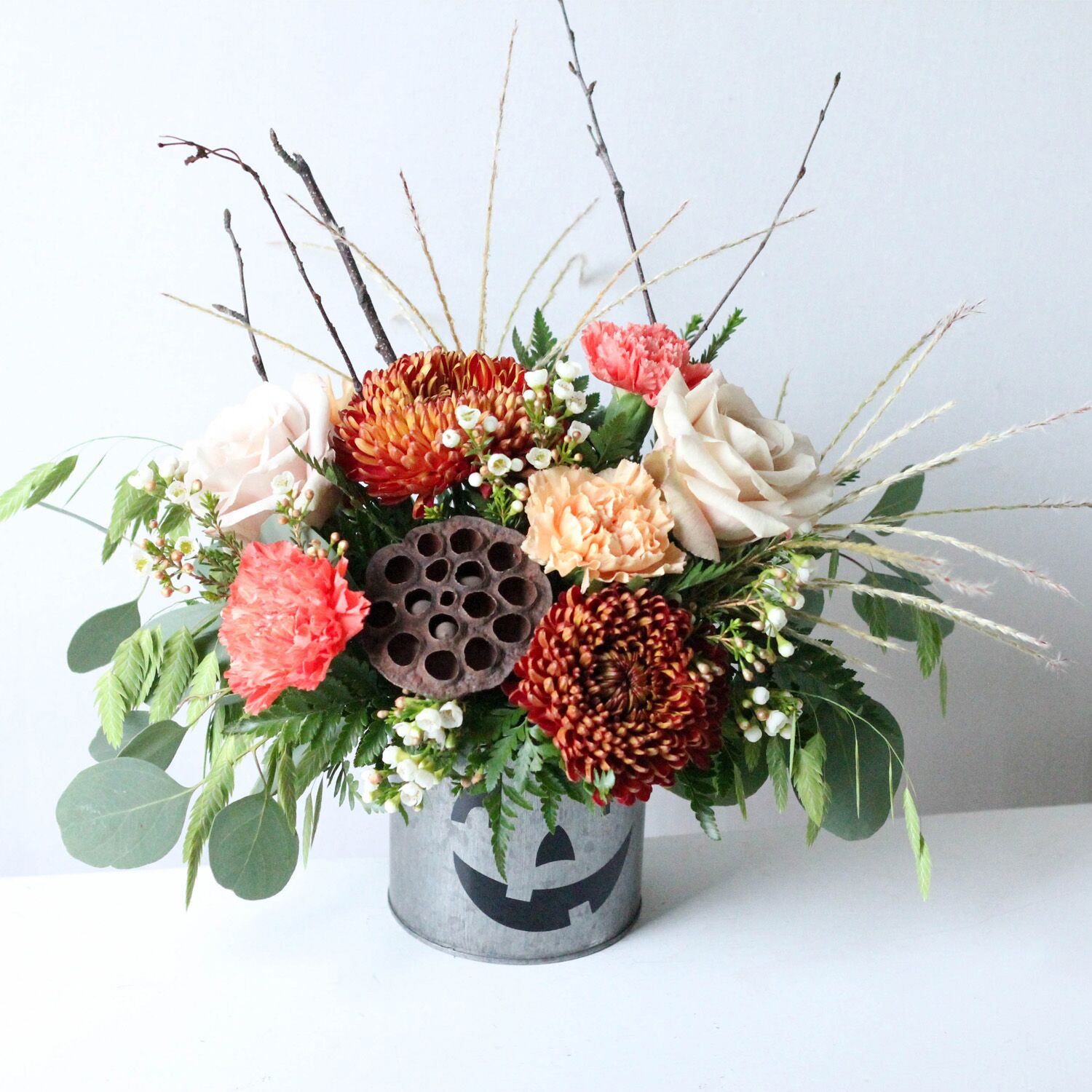 Silver Jack - A flower pot painted to resemble a Jack-O-Lantern with a flower arrangement