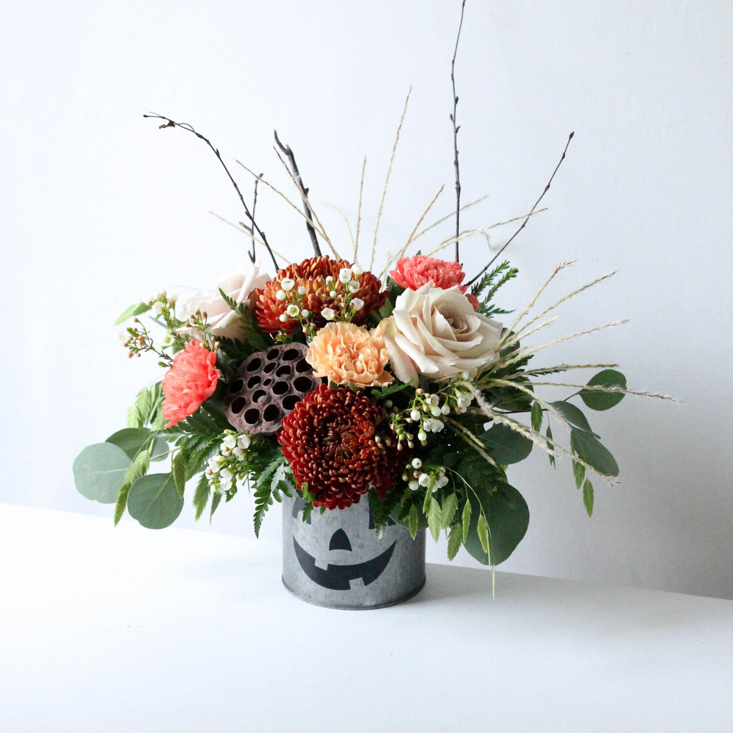 Silver Jack - A flower pot painted to resemble a Jack-O-Lantern with a flower arrangement