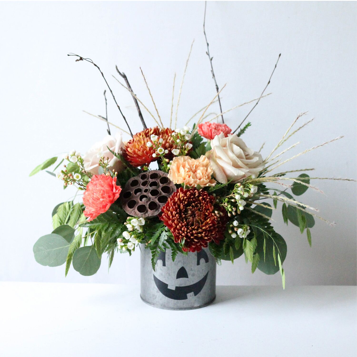 Silver Jack - A flower pot painted to resemble a Jack-O-Lantern with a flower arrangement